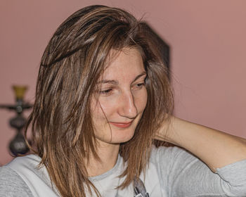 Close-up portrait of a smiling young woman against wall