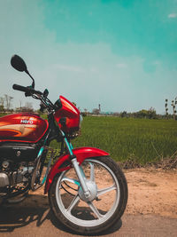 Bicycle parked on field by road against sky