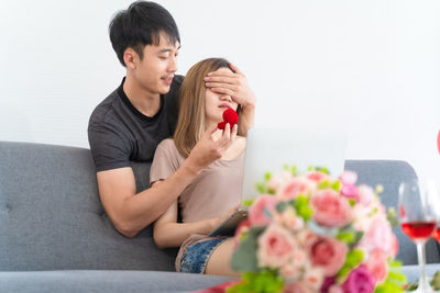 Woman holding rose while sitting on sofa