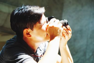 Man photographing through camera against wall