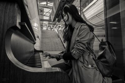 Young woman playing piano in building