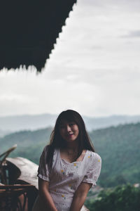 Portrait of beautiful woman standing against sky