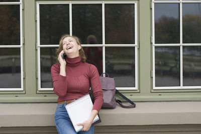 A young girl back to school, stands with a backpack and talks on the phone