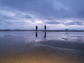 Silhouette people on beach against sky