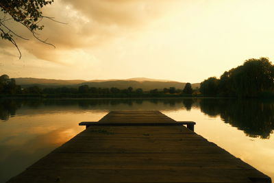 Pier over lake against sky during sunset