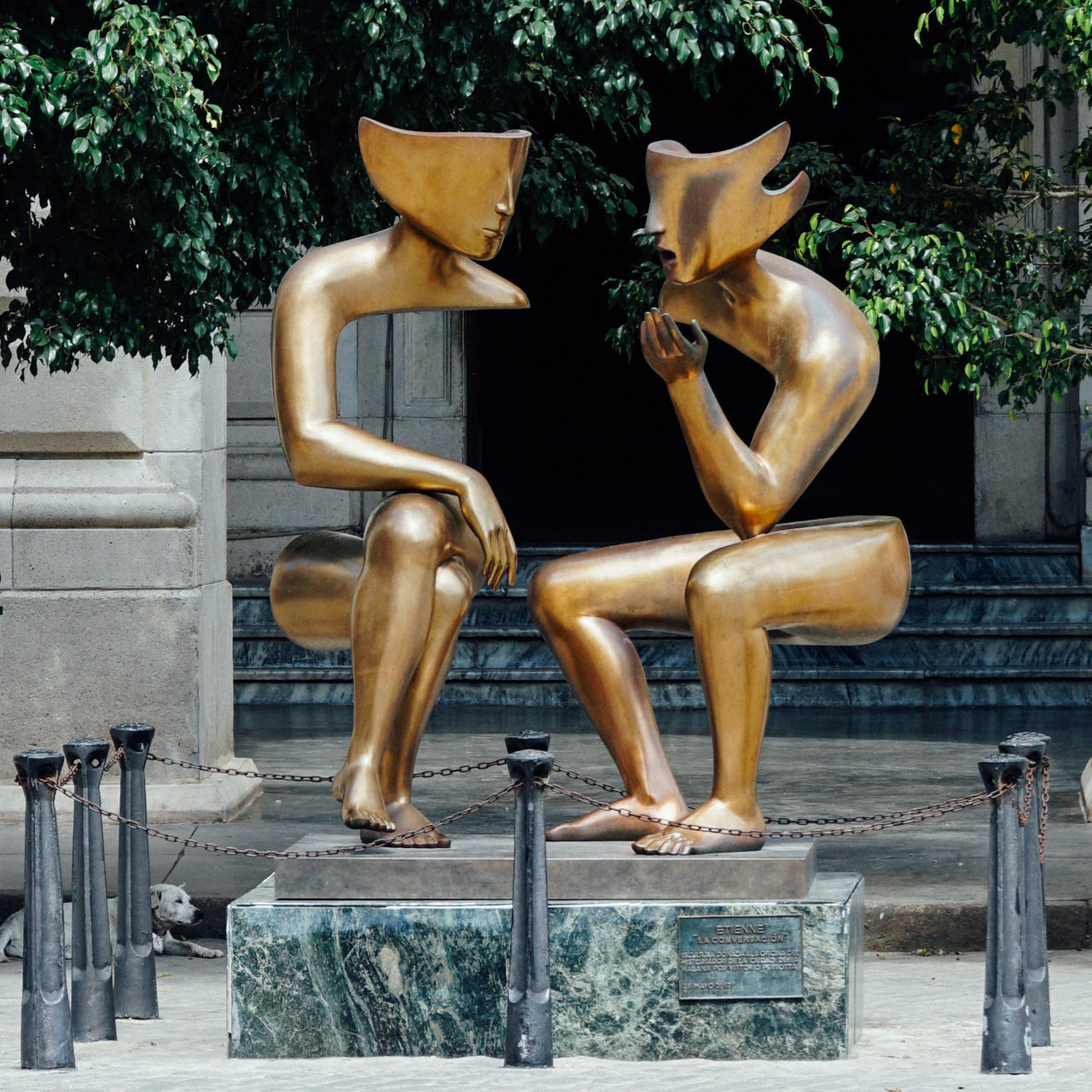 STATUE OF MAN SITTING AGAINST PLANTS