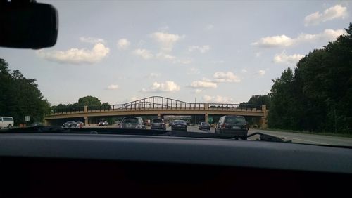 Cars on road against cloudy sky