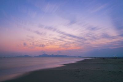 Scenic view of beach against dramatic sky at sunset