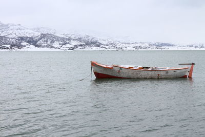 Boat in sea against sky during winter