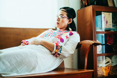 Portrait of young woman sitting on bed at home