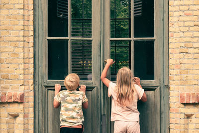 Rear view of brother and sister in building