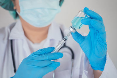 Midsection of doctor holding syringe at hospital