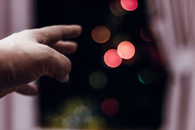 Defocused image of hand holding illuminated christmas lights