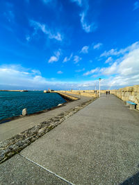 Surface level of road by sea against blue sky