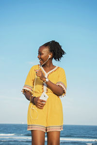 Woman standing by sea against sky