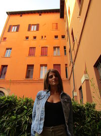 Low angle view of young woman looking away against building