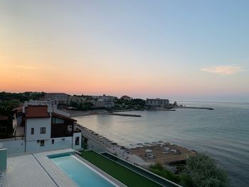 High angle view of buildings by sea against sky during sunset