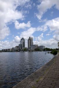 Buildings by river against sky in city