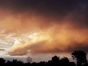 Low angle view of sunlight streaming through clouds during sunset