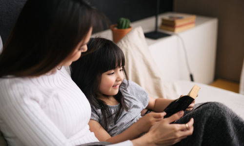 High angle view of mother and daughter siting on sofa at home