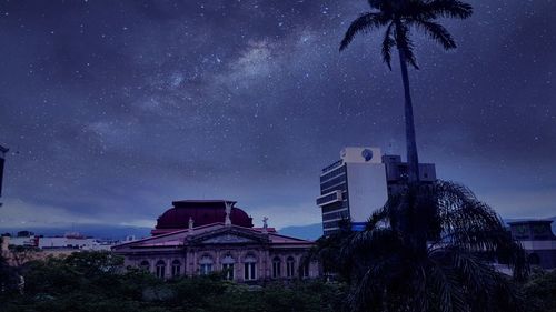 Houses and trees against sky at night