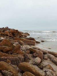 Scenic view of rocks on beach against sky