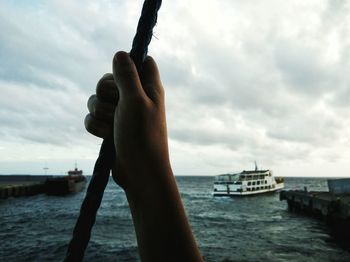 Close-up of man on boat in sea against sky