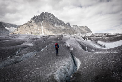 Rear view of person on snowcapped mountain against sky