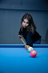 Portrait of young woman playing pool