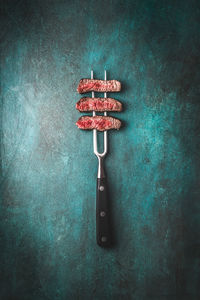 Close-up of red pipe on table against wall