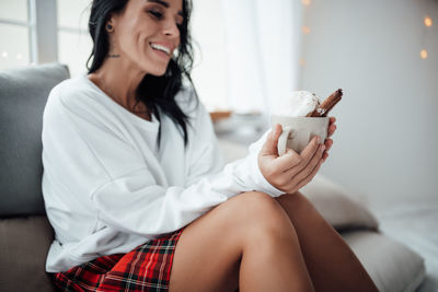 Smiling woman holding hot chocolate sitting at home