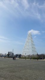 People at metallic structure at town square with eiffel tower against sky