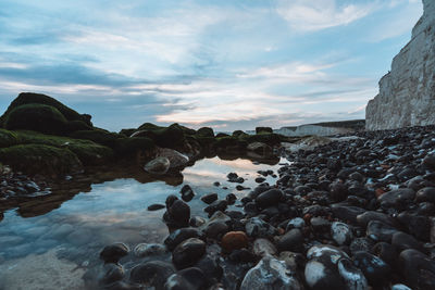 Rocks on beach against sky during sunset