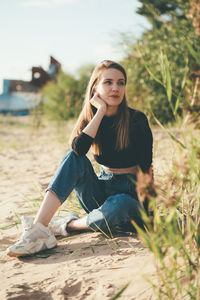 Beautiful woman sitting on land looking away