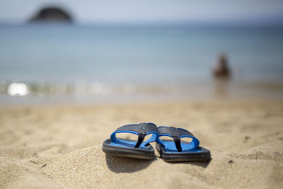 Blue slippers on the beach against the background of the sea