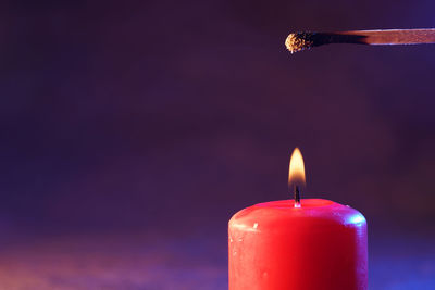 Close-up of burning candle against black background