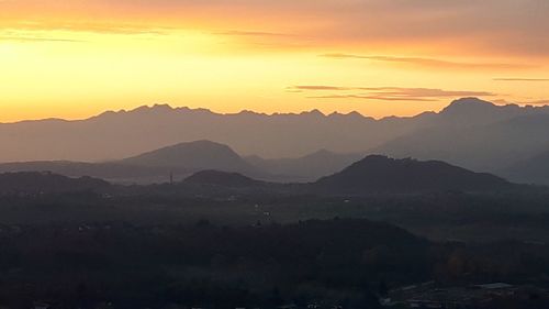 Scenic view of silhouette mountains against orange sky