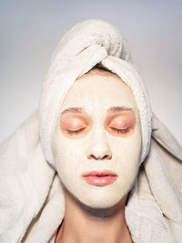 Closeup portrait woman facial mud mask hair wrapped in towel