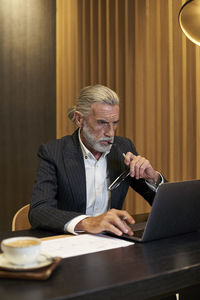 Midsection of man using mobile phone while sitting on table