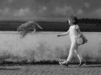 Full length of girl walking against graffiti on wall