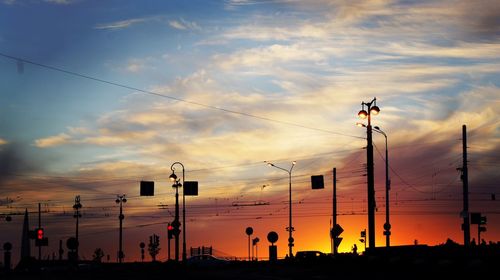 Silhouette street lights against orange sky