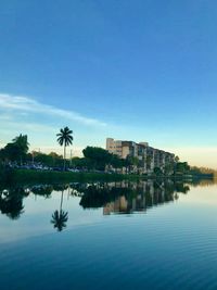 Buildings by lake against blue sky