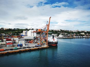 Cranes at harbor against sky in city