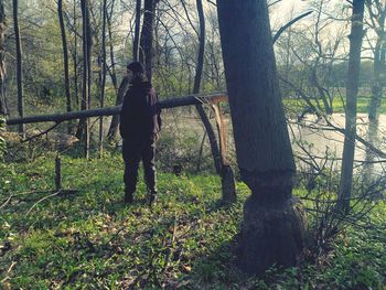 Man standing by tree trunk in forest