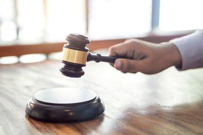 Cropped hand of lawyer striking gavel on table