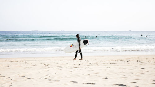 Rear view of woman on beach against clear sky