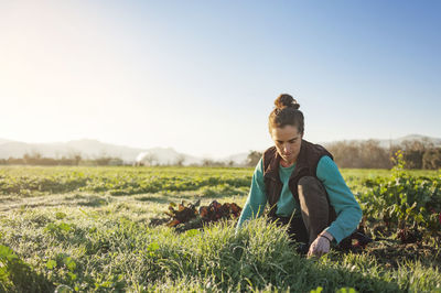 Woman gardening in field against clear sky