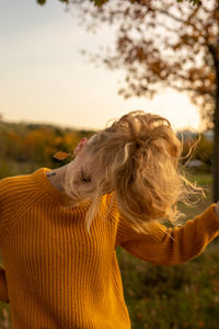 Midsection of woman on field against sky during sunset