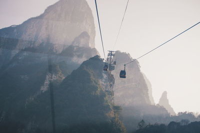 Low angle view of overhead cable cars against mountains