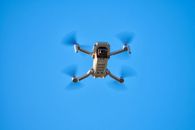 Low angle view of airplane flying against clear blue sky